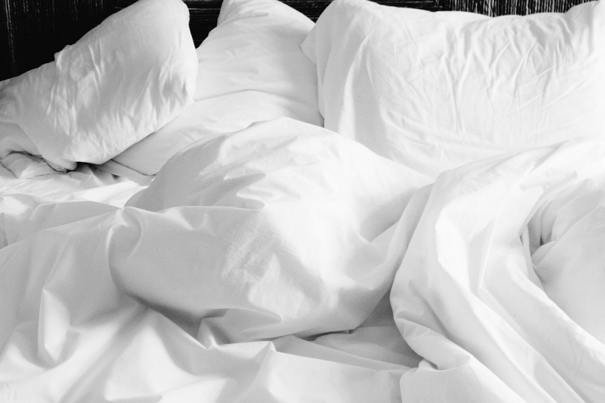 Unmade bed with white sheets and pillows