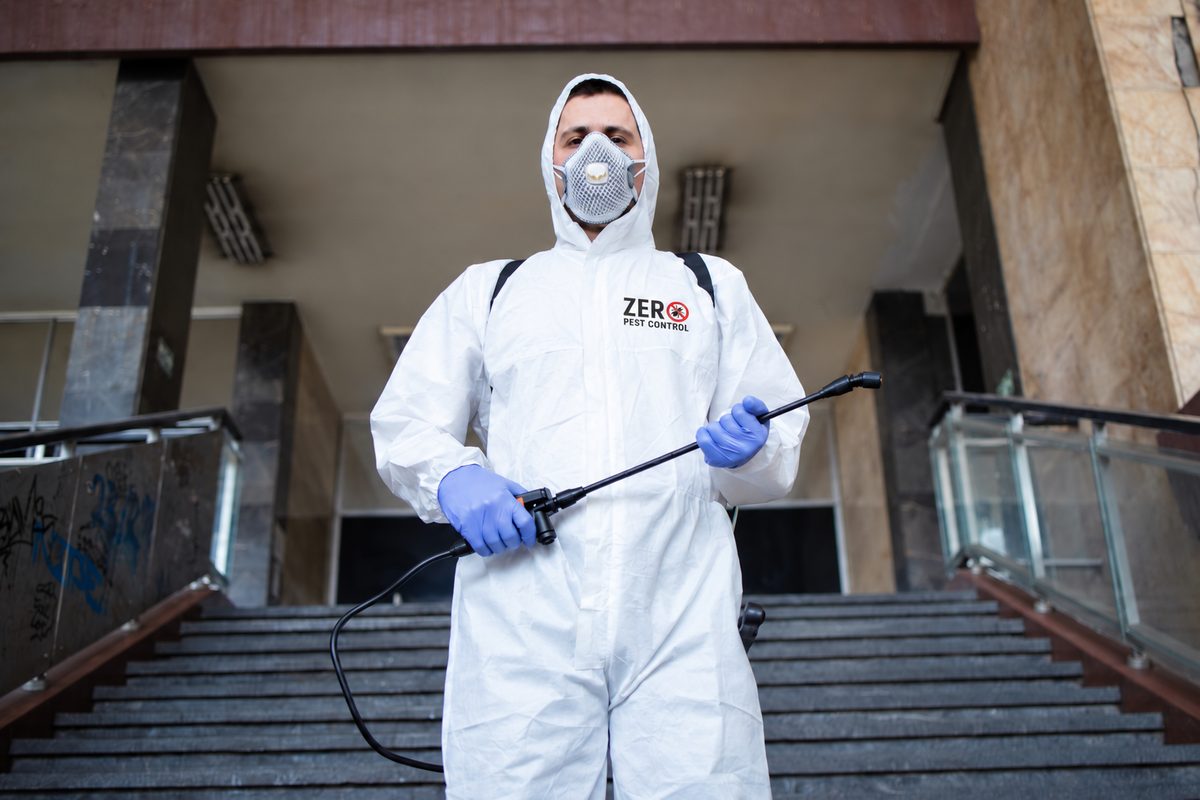 Zero Pest Control technician in a protective suit holding a sprayer